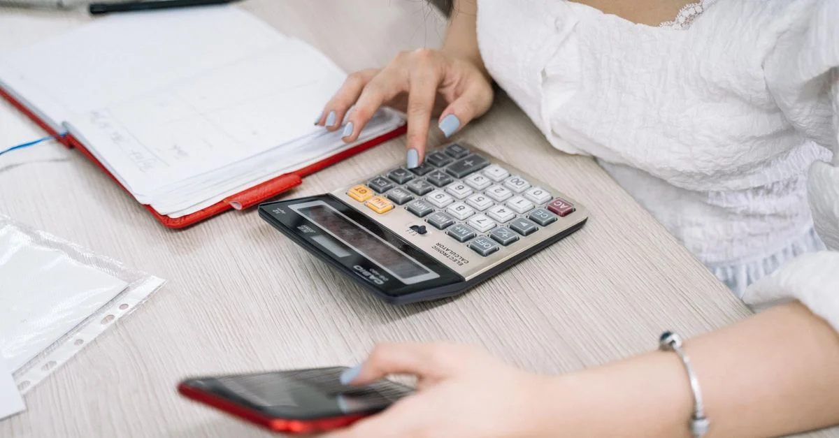 Gros plan sur une femme utilisant une calculatrice et un téléphone à son bureau.