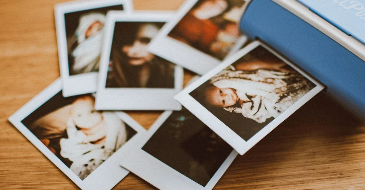 Une collection d'impressions photo instantanées éparpillées sur une table en bois, mettant en avant des moments personnels.