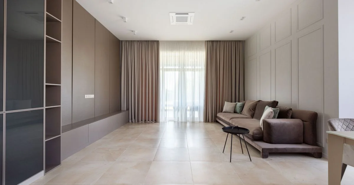 Intérieur spacieux et moderne de salon avec un sofa, des étagères et des rideaux.