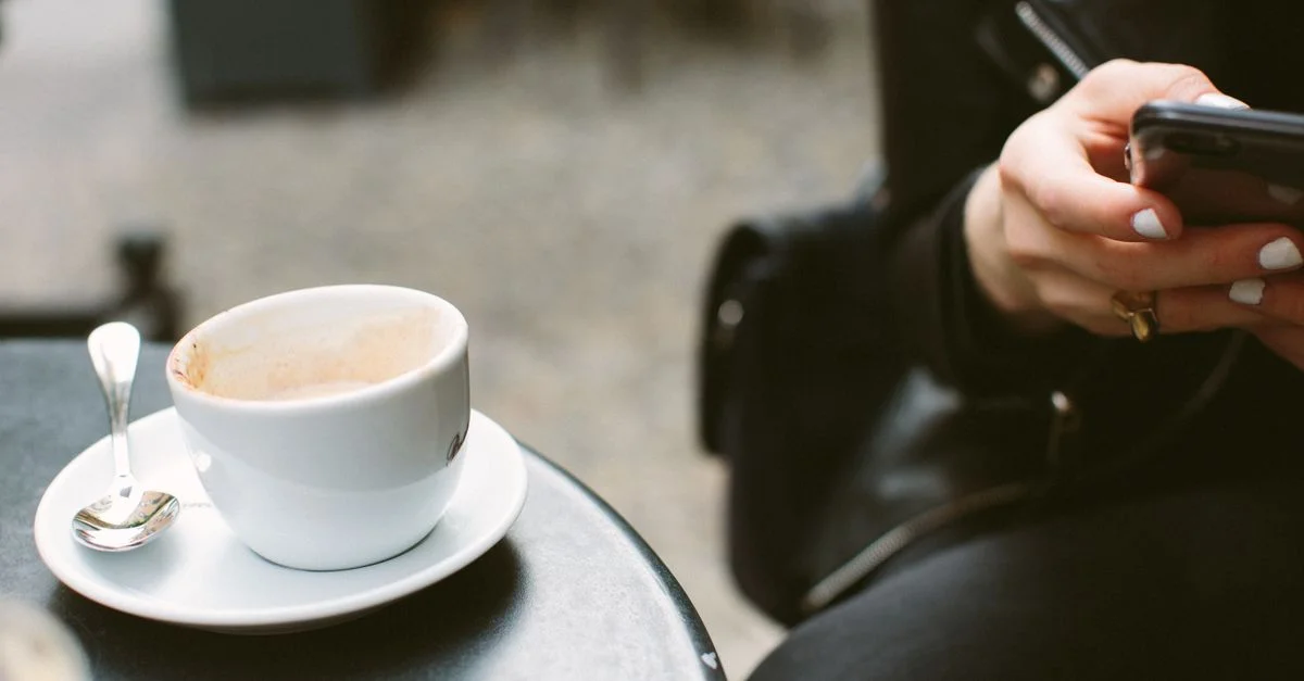 Scène de café confortable avec du café, un smartphone et une ambiance décontractée.