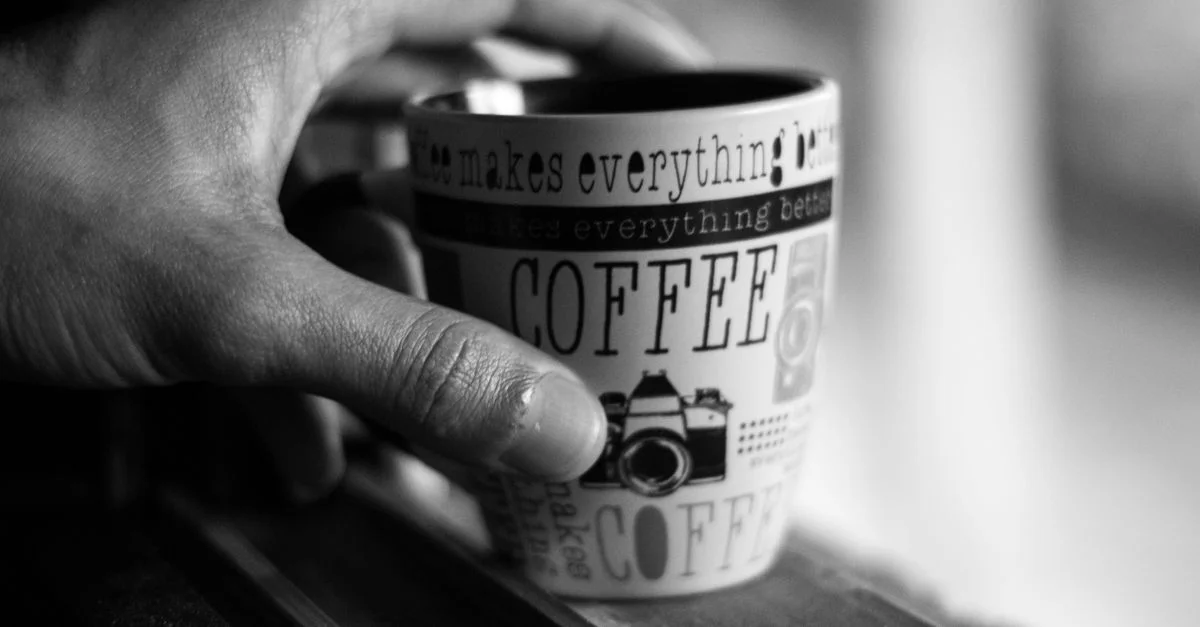 Une photo en noir et blanc d'une main tenant une tasse à café avec un texte inspirant et un design d'appareil photo.