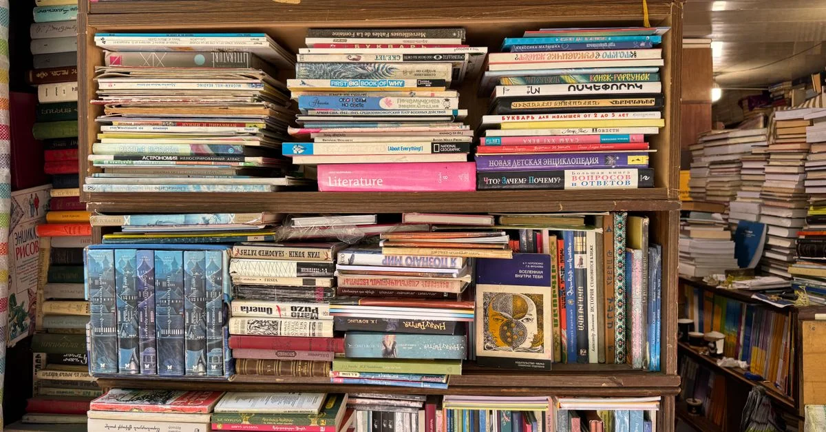 Une bibliothèque chargée de divers livres dans une librairie de Yerevan, présentant différents genres et langues.
