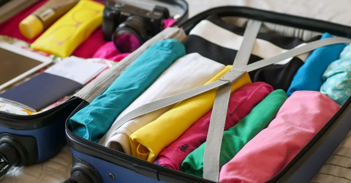 Valise ouverte soigneusement rangée avec des vêtements colorés et des essentiels de voyage.